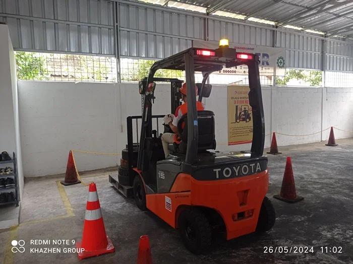 Peserta berlatih manuver forklift di antara kerucut pembatas di workshop Khazhen